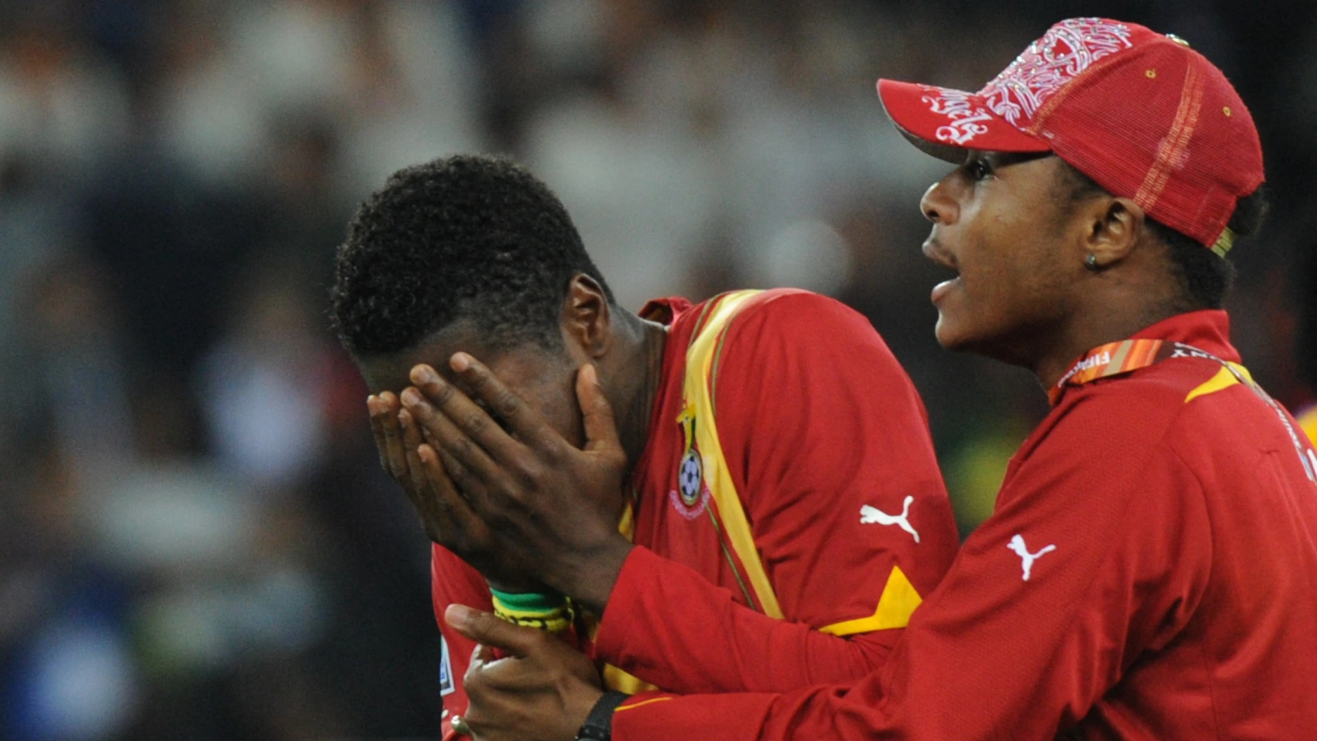 Ghana's striker Asamoah Gyan (L) is comforted by a trainer at the end of the 2010 World Cup quarter-final match Uruguay vs. Ghana on July 2, 2010.