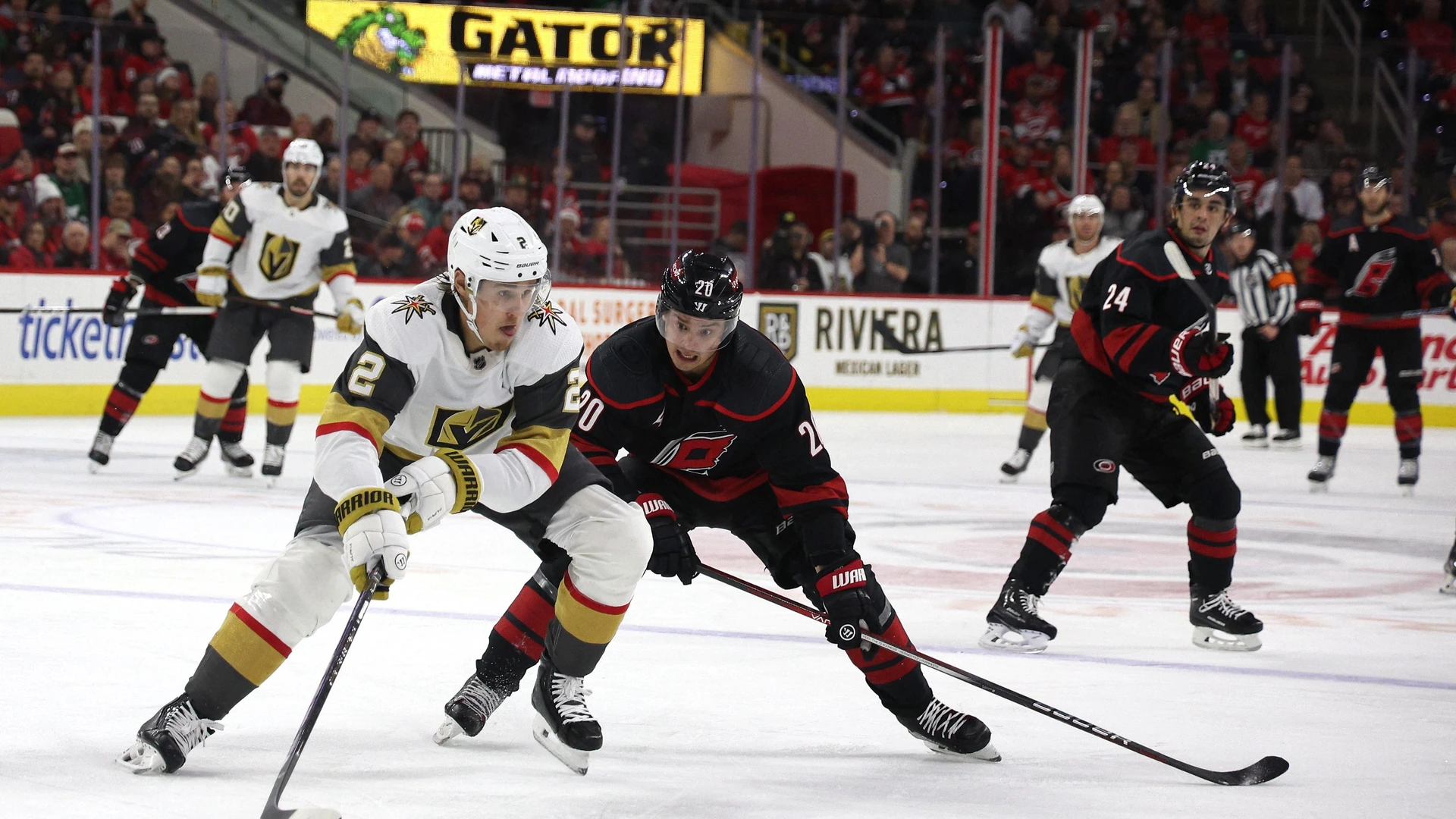 Zach Whitecloud #2 of the Vegas Golden Knights skates with the puck while defended by Sebastian Aho #20 of the Carolina Hurricanes during  the game  December 19, 2023