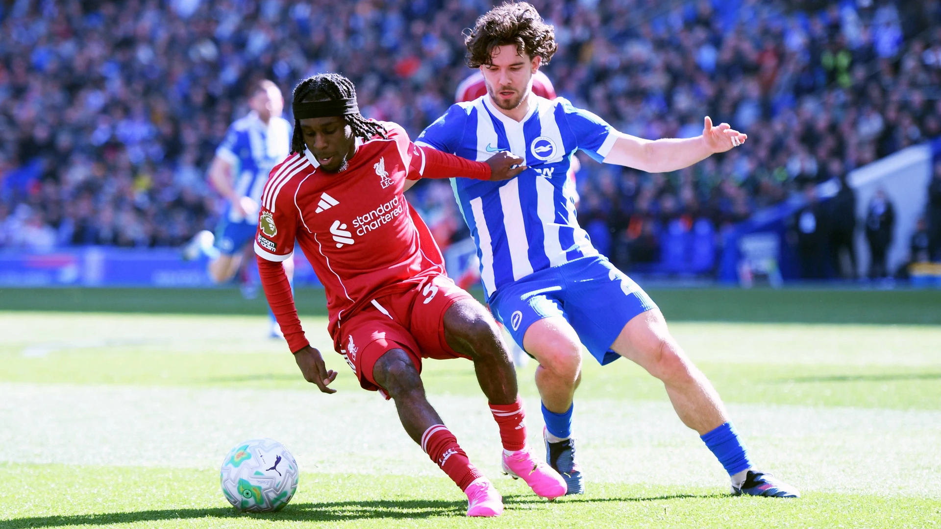 Jeremie Frimpong Defender of Liverpool and Ferdi KadÄoÄülu Defender of Brighton and Hove Albion jostles for the ball during the Premier League match between Brighton and Hove Albion and Liverpool a on 21 March 2026