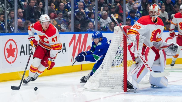 VANCOUVER, CANADA - OCTOBER 9: Connor Zary #47 of the Calgary Flames is pursued by Jake DeBrusk #74 of the Vancouver Canucks during the first period of their NHL game at Rogers Arena on October 9, 2024 in Vancouver, British Columbia, Canada.