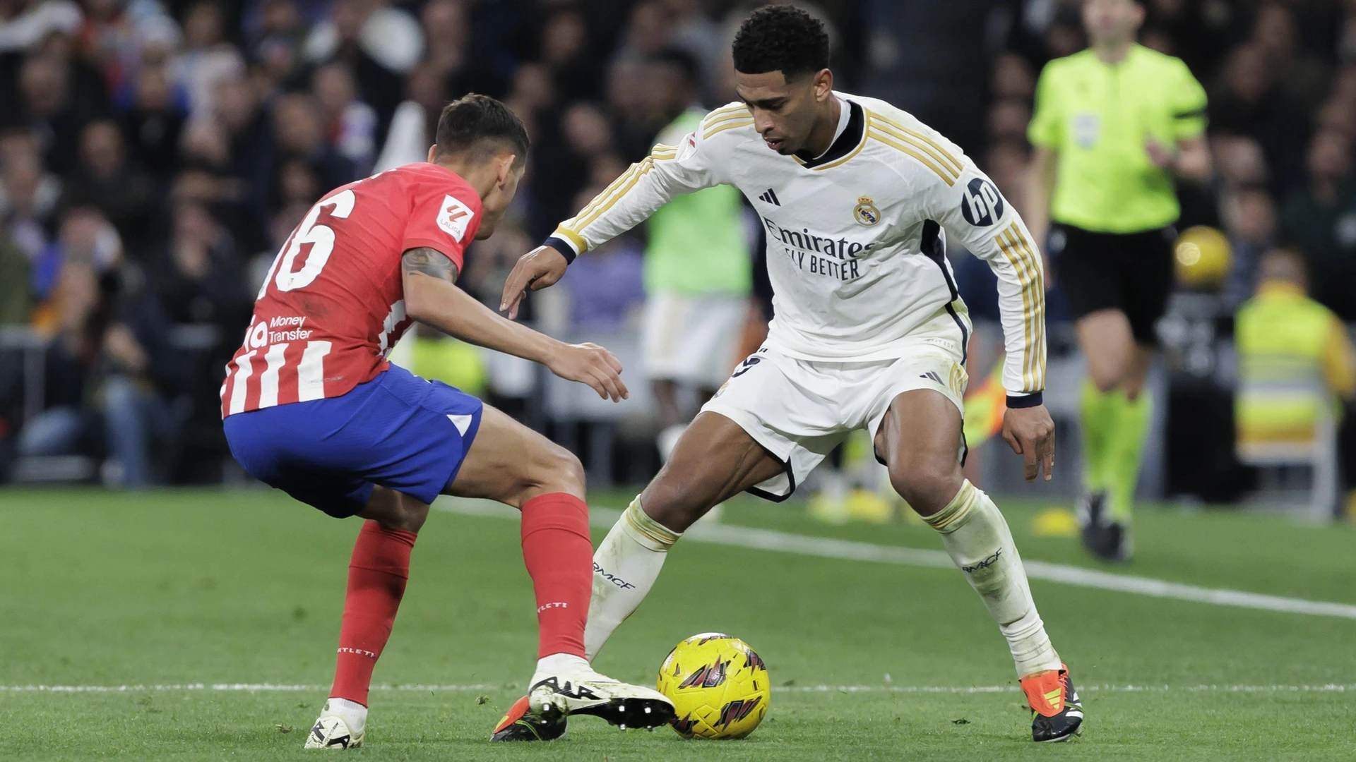 Jude Bellingham of Real Madrid and Nahuel Molina of Atletico de Madrid are fighting for the ball during the La Liga 2023/24 match between Real Madrid and Atletico de Madrid at Santiago Bernabeu Stadium in Madrid, Spain
