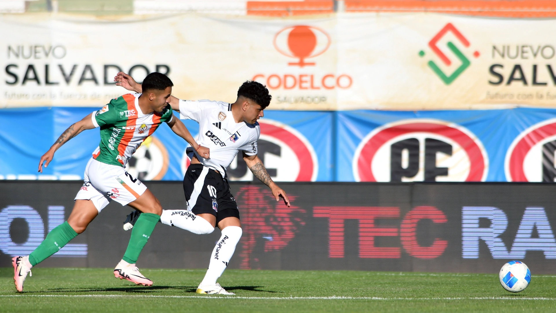 Colo Colo player Claudio Aquino, center, vies for the ball against Aaron Astudillo of Cobresal during the first division league match at the El Cobre stadium in El Salvador, Chile. 28/11/2025